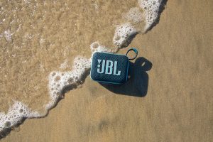 JBL Go 4 sur le sable d'une plage : une enceinte résistante à l'eau et à la poussière