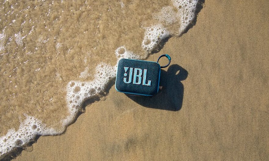 JBL Go 4 sur le sable d'une plage : une enceinte résistante à l'eau et à la poussière