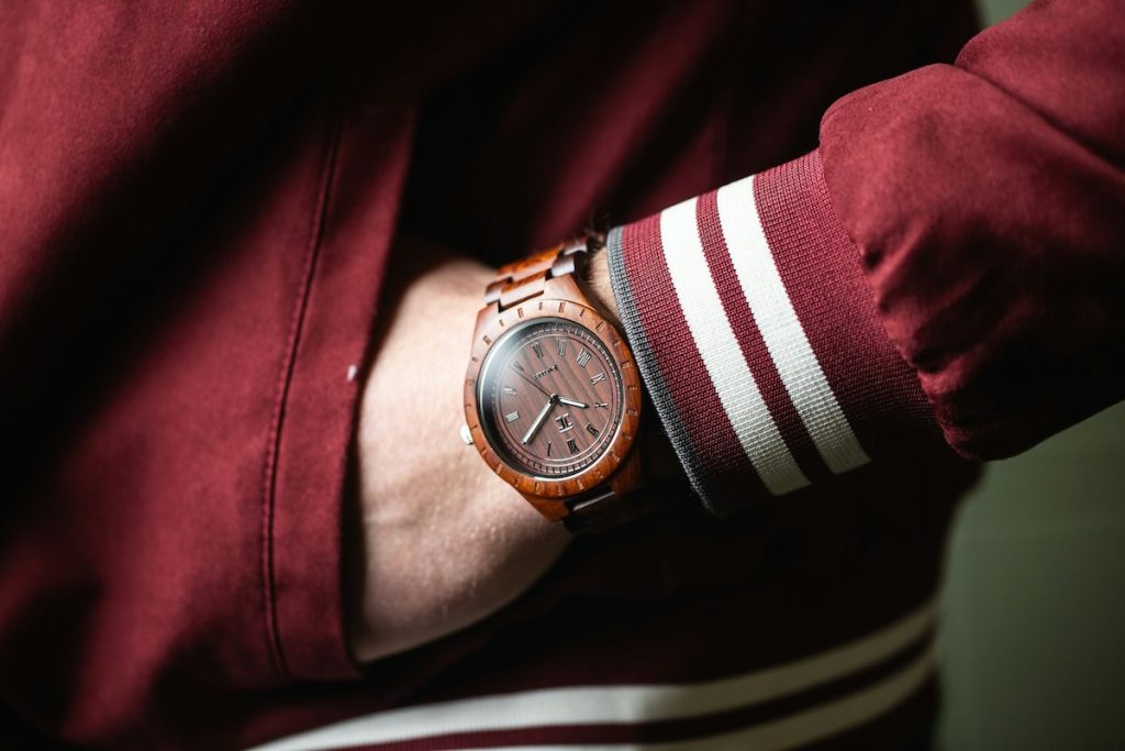 Montre en bois portée au poignée d'un homme habillé en teddy rouge